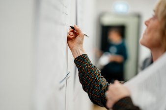 Eine Teilnehmerin schreibt mit einem Filzstift auf ein Poster.