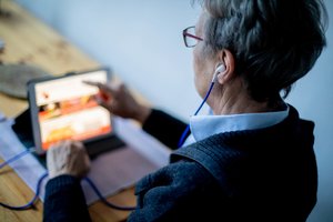 Eine ältere Dame bedient ein Tablet.