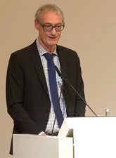 Christian Luft, Staatssekretär des Bundesministeriums für Gesundheit steht an einem Pult und hält ein Grußwort.