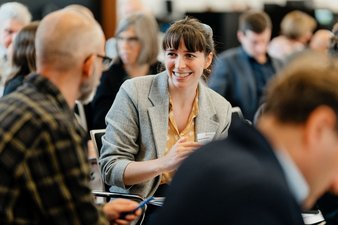 Ein Tagungsteilnehmer und eine Tagungsteilnehmerin unterhalten sich miteinander zum Konzeptpapier.