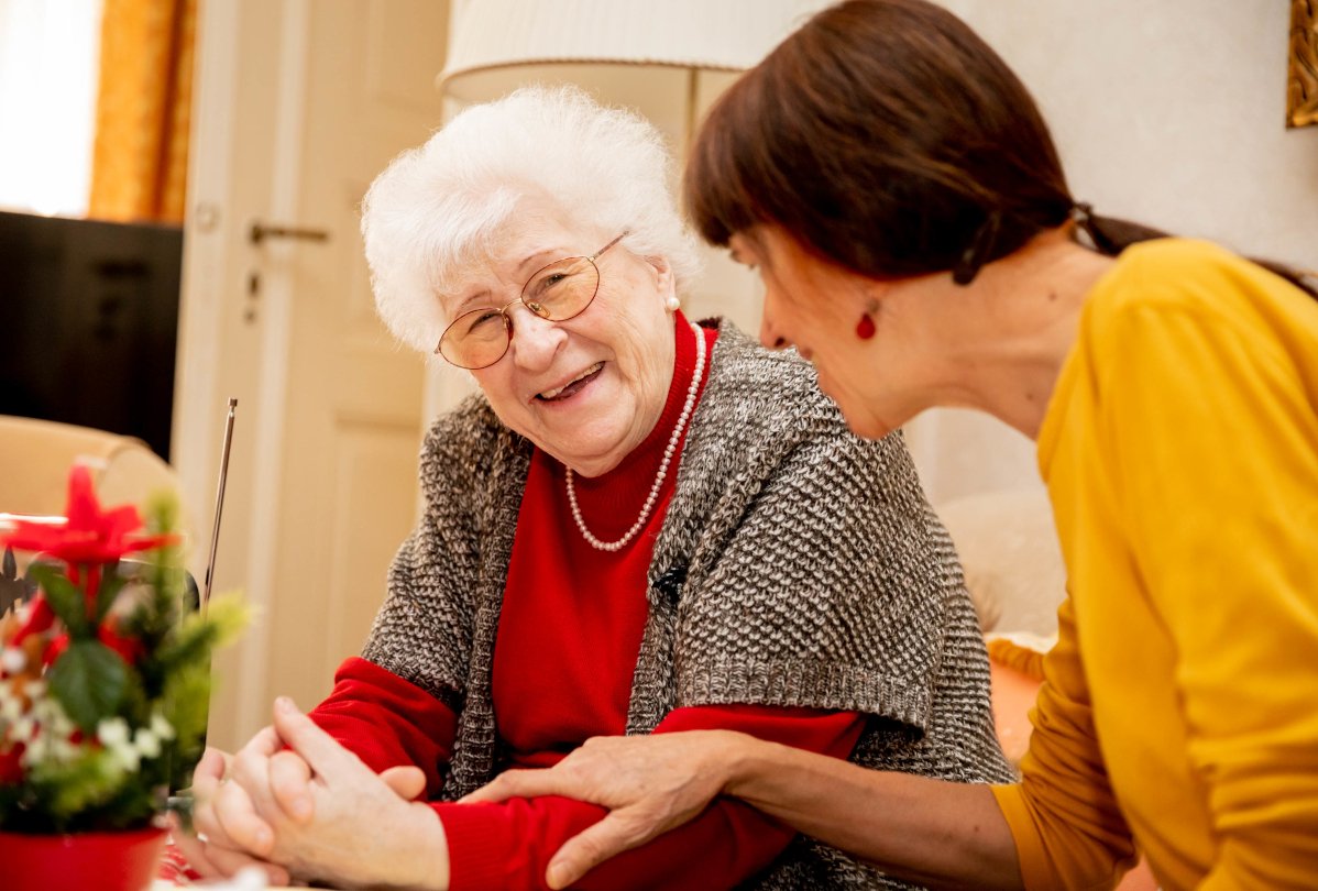 Eine Seniorin und eine Pflegerin lachen gemeinsam