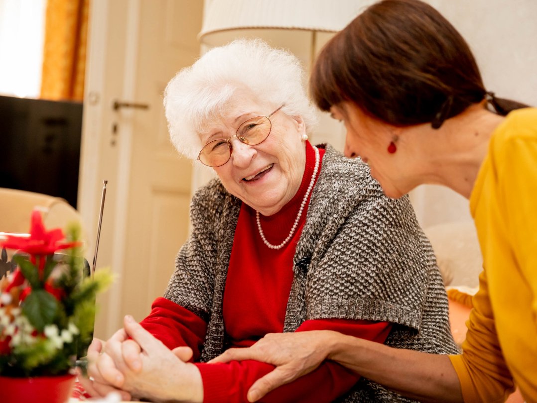 Eine Seniorin und eine Pflegerin lachen gemeinsam