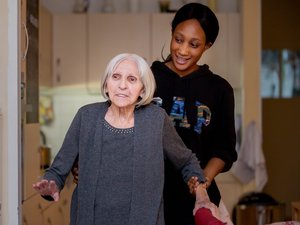 Eine Pflegerin stützt eine ältere Frau beim Gehen