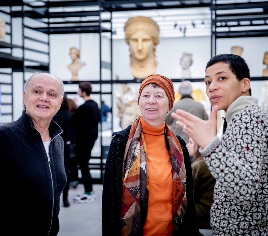 Zwei ältere Personen auf einer Kunstausstellung im Gespräch mit einer Museumsführerin.