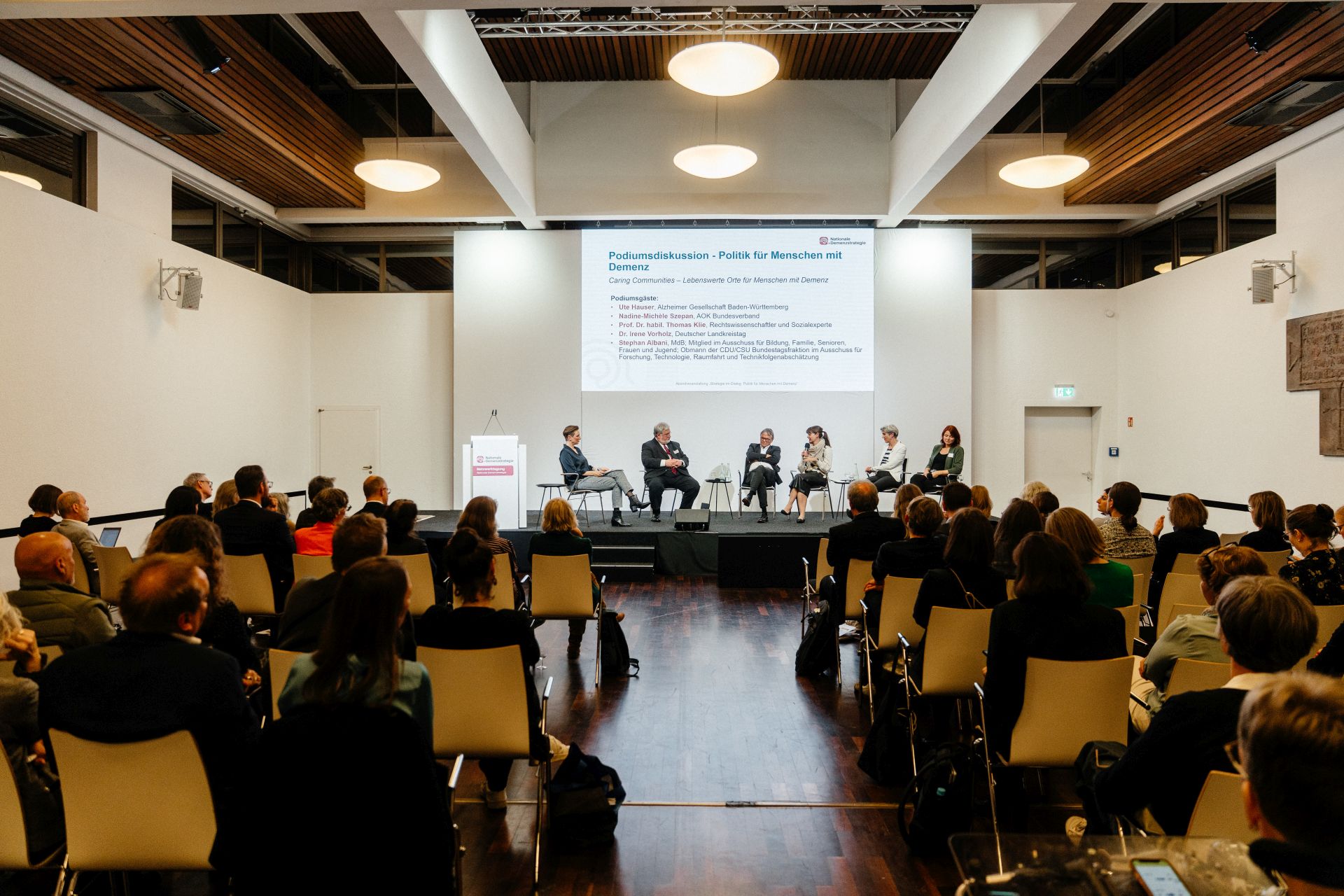 Blick durchs Publikum auf die Podiumsdiskussion auf der Abendveranstaltung "Strategie im Dialog: Politik für Menschen mit Demenz". 